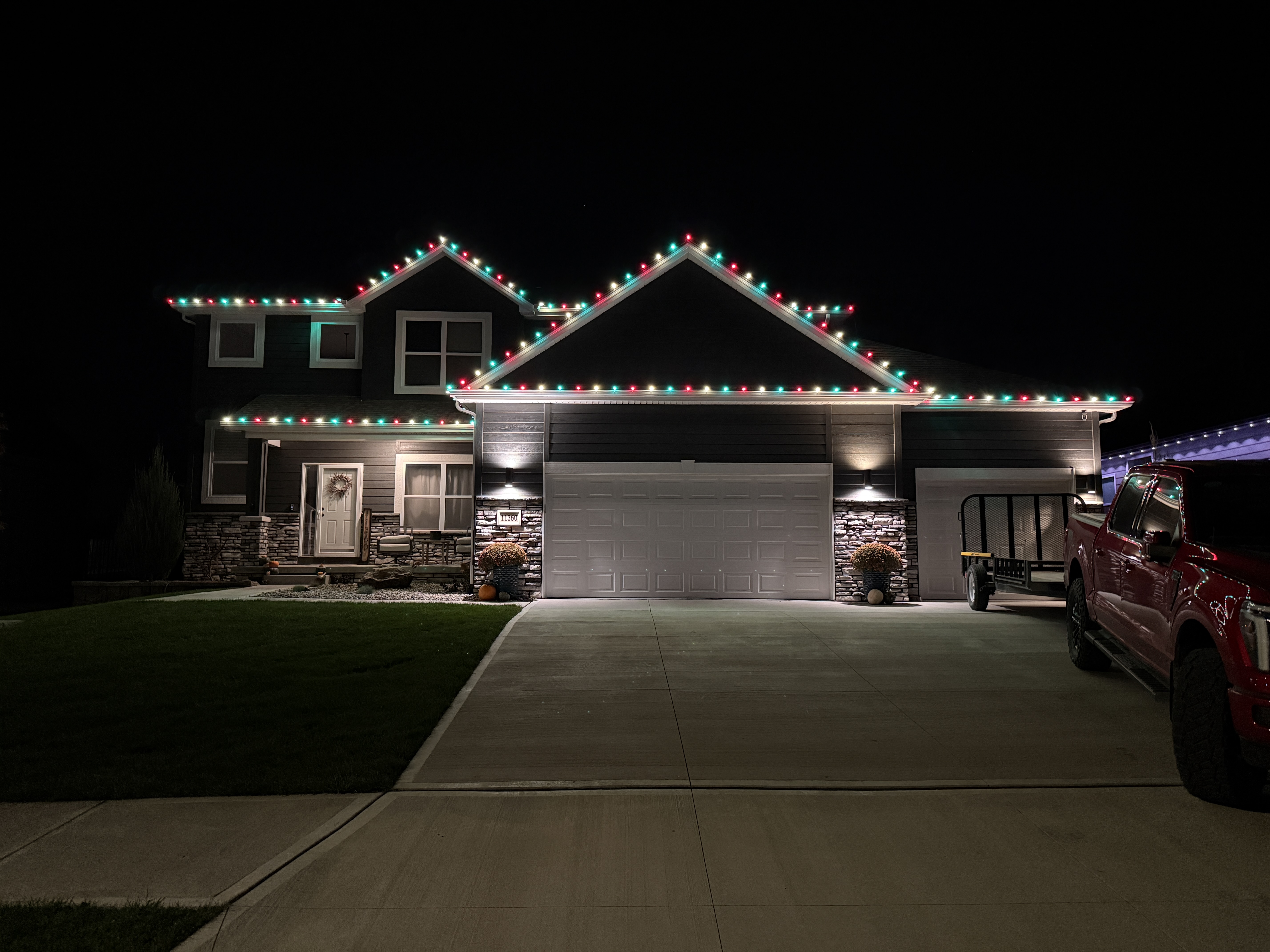 Two-story home with red, green, and white C9 roofline lights installed by SomeGuys