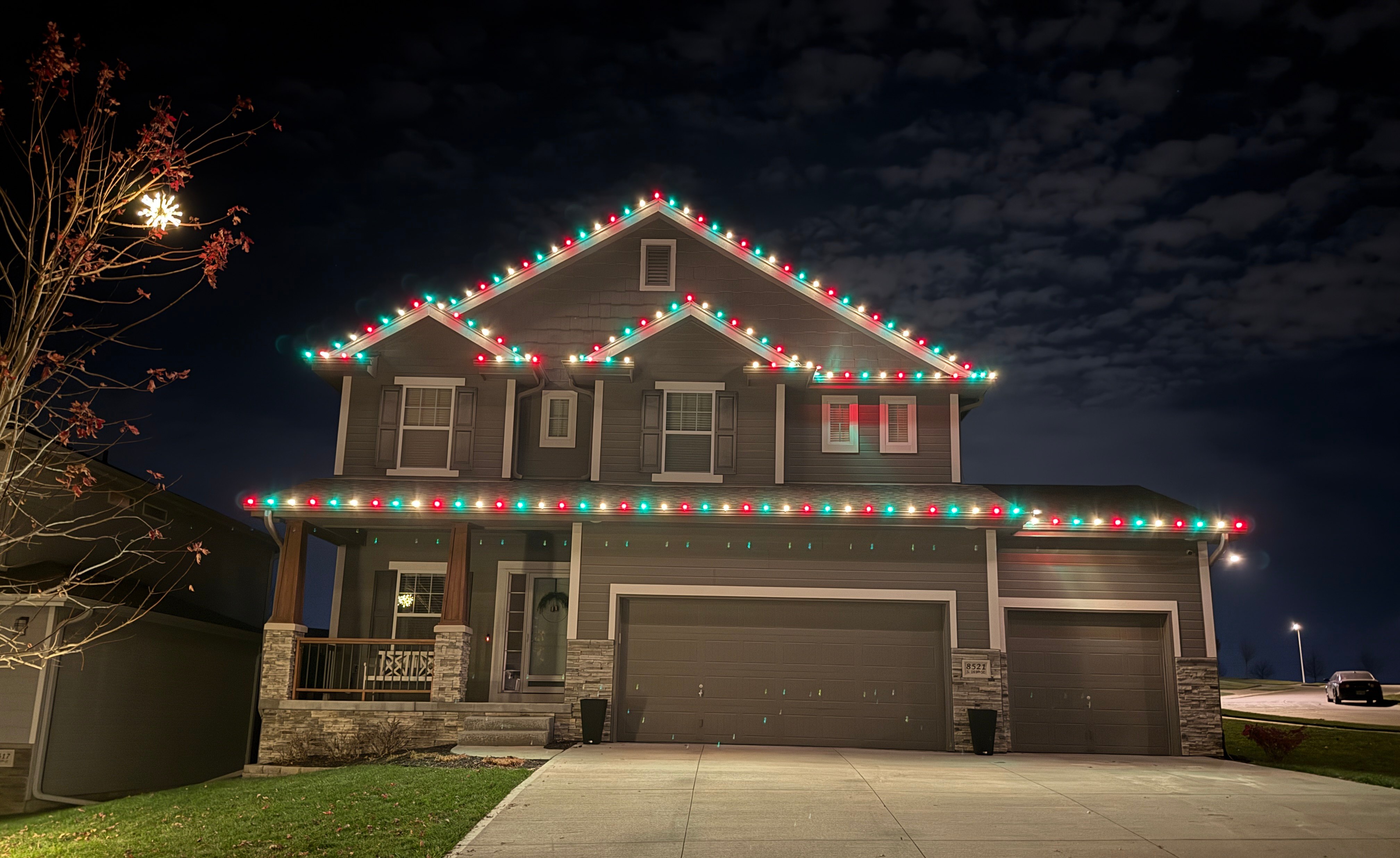 Craftsman home with crisp red, green and white C9 bulbs following every gable and peak