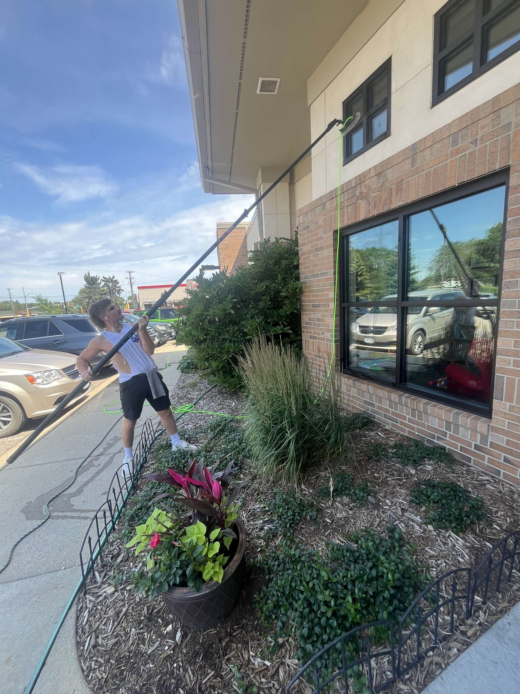 Window cleaning technician with water-fed pole cleaning commercial brick building windows